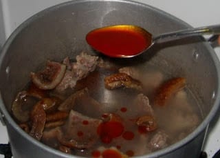 Adding palm oil to a pot of food